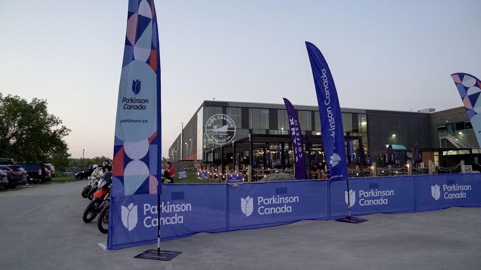 Parkinson Canada flags and banners outside Side Launch Brewing at dusk
