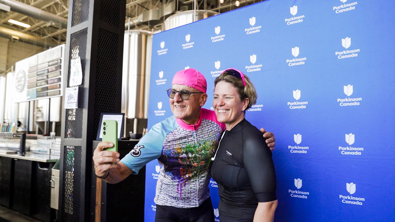 Two riders taking a selfie at the Parkinson Canada backdrop